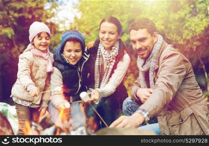 hike, travel, tourism and people concept - happy family roasting marshmallow over campfire. happy family roasting marshmallow over campfire