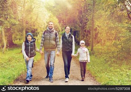hike, travel, tourism and people concept - happy family walking with backpacks in woods. happy family with backpacks hiking in woods