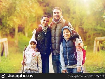 hike, travel, tourism and people concept - happy family walking with backpacks in woods. happy family with backpacks hiking