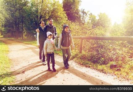 hike, travel, tourism and people concept - happy family walking with backpacks in woods. happy family with backpacks hiking in woods