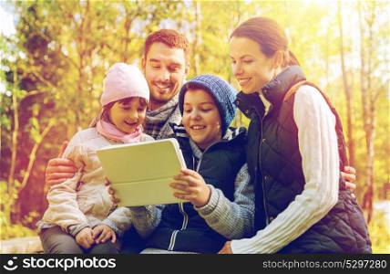 hike, travel, tourism and people concept - happy family with tablet pc computer at camp in woods. happy family with tablet pc at camp