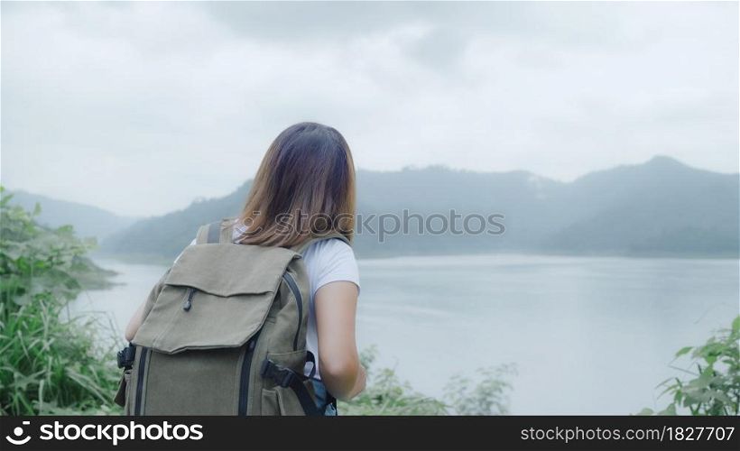 Hiker backpacker woman on hiking adventure feeling freedom walking in forest near lake in rainy day. Lifestyle women travel relax concept.