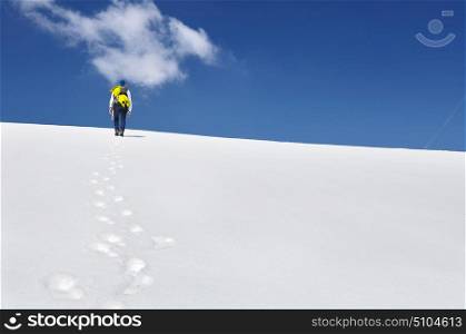 hiker climbing mountain in the snow and under blue sky