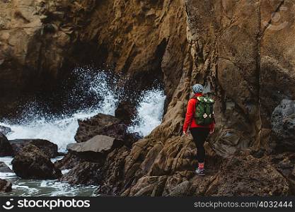 Hiker climbing over rocks, Big Sur, California, USA