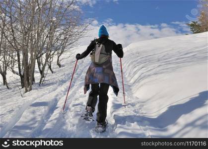 hiker climbing snowy montains with snowshoes