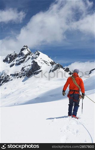 Hiker connected to safety line in snowy mountains back view
