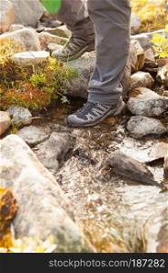 hiker crossing a river. legs in boots
