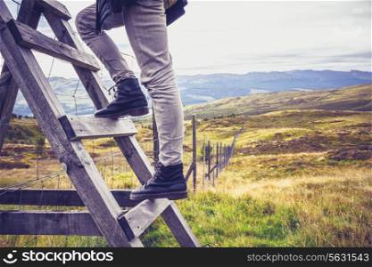 Hiker crossing a stile in the mountains