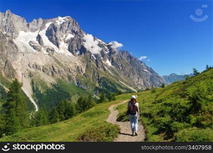 hiker in action in Ferret valley with Mont Blanc massif on background