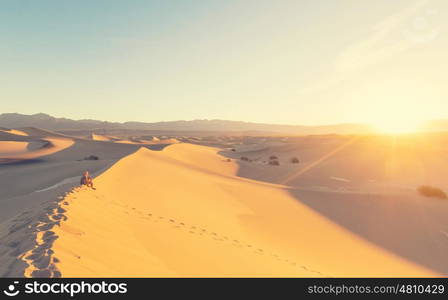 Hiker in sand desert. Sunrise time.