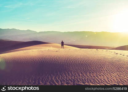 Hiker in sand desert. Sunrise time.