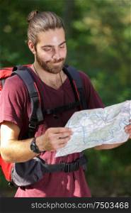 hiker man looking to map standing in forest