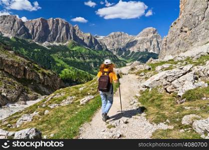 hiker on footpath in Sella mountain, on background Colfosco and Badia Valley, south Tyrol, Italy