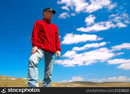 Hiker on the field against sun and cloudscape