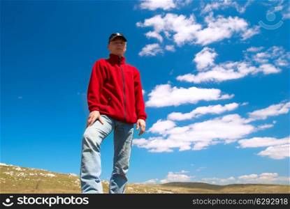 Hiker on the field against sun and cloudscape
