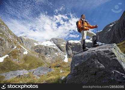 Hiker on top of boulder in mountains