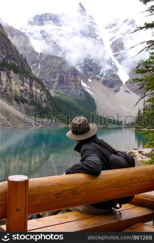 Hiker pauses on wooden bench at Lake Moraine Lake