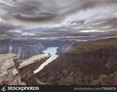 Hiker sitting in Trolltunga cliff, Norway