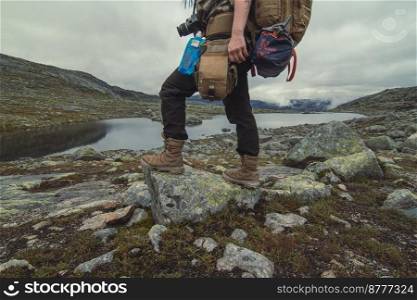 Hiker standing on rock near narrow river scenic photography. Picture of person with mountains on background. High quality wallpaper. Photo concept for ads, travel blog, magazine, article. Hiker standing on rock near narrow river scenic photography