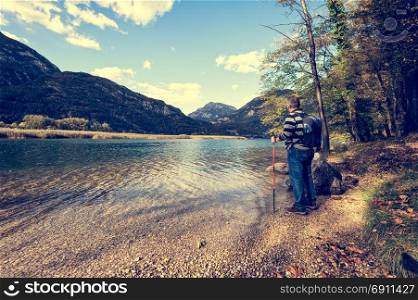 Hiker standing on the shore of the lake among the mountains admiring the landscape.