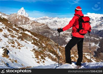 Hiker takes a rest admiring the Matterhorn peak. Sunny day, early winter. Matterhorn Massif, Valle d&rsquo;Aosta, Italy, Europe.