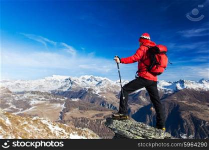 Hiker takes a rest admiring the mountain landscape. Sunny day, early winter. Monte Rosa Massif, Valle d&rsquo;Aosta, Italy, Europe.