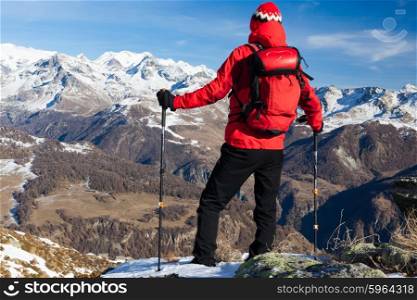 Hiker takes a rest admiring the mountain landscape. Sunny day, early winter. Monte Rosa Massif, Valle d&rsquo;Aosta, Italy, Europe.