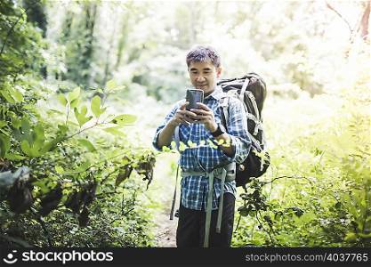 Hiker taking photo with camera phone in forest