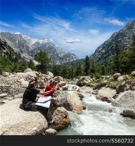 Hiker trekkers read a trekking map on trek in Himalayas mountains. Himachal Pradesh,India