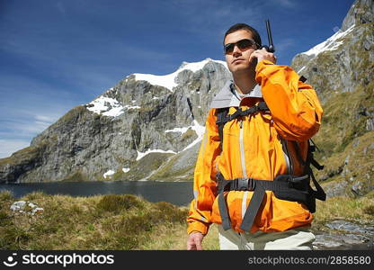 Hiker using walkie-talkie on mountain trail