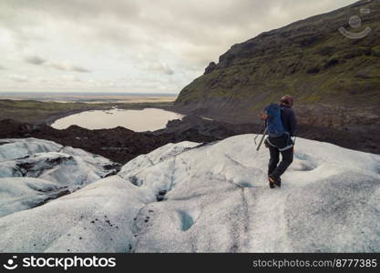 Hiker walking across snowy valley landscape photo. Beautiful nature scenery photography with lake on background. Idyllic scene. High quality picture for wallpaper, travel blog, magazine, article. Hiker walking across snowy valley landscape photo