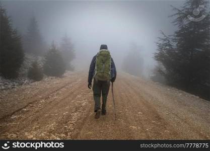 hiker walks along the road in the fog