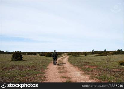 Hiker with a backpack at a winding dirt road at the island Oland in Sweden