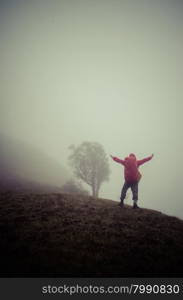 Hiker with backpack standing on top of a mountain and enjoying