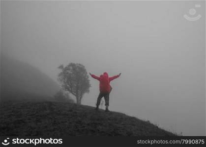 Hiker with backpack standing on top of a mountain and enjoying