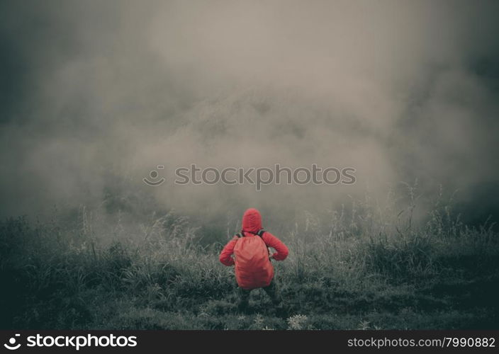 Hiker with backpack standing on top of a mountain and enjoying