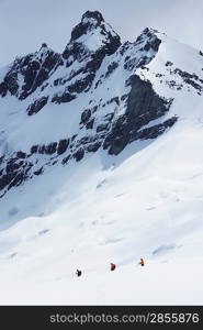 Hikers headed for distant peak in snow back view