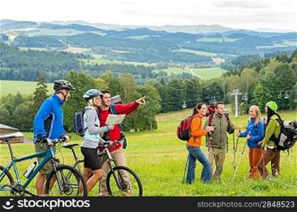 Hikers helping cyclists following track in nature landscape