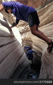 Hikers Scaling A Rock Crevice