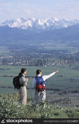 Hikers Standing On A Point Overlooking A Mountain Valley