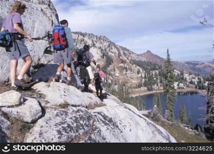 Hikers Traversing A Rocky Ridge Overlooking A Lake