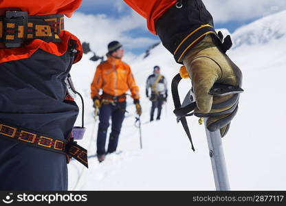 Hikers using walking sticks in snowy mountains mid section on front man