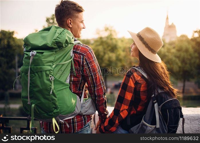 Hikers with backpacks go sightseeing in tourist town on vacation. Summer hiking. Hike adventure of young man and woman. Hikers go sightseeing in tourist town on vacation