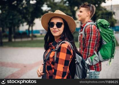 Hikers with backpacks on excursion in tourist town. Summer hiking. Hike adventure of young man and woman. Hikers with backpacks on excursion in tourist town