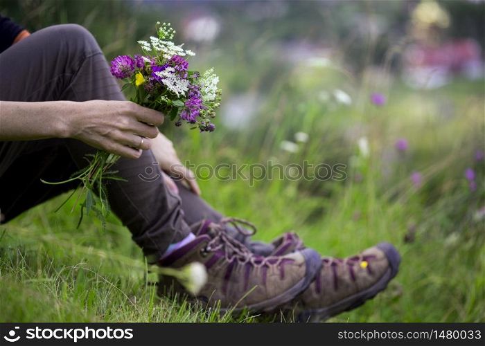 hiking boots close-up. girl tourist in boots and with a bouquet of wild flowers. active lifestyle
