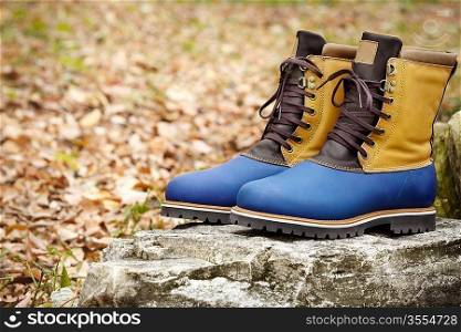 Hiking Boots on the autumn foliage background, selective focus on foreground