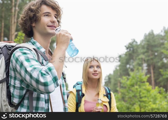 Hiking couple drinking energy drinks in forest