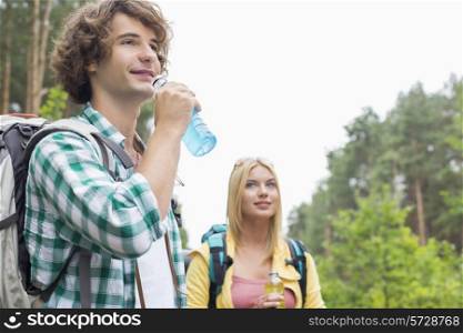 Hiking couple drinking energy drinks in forest
