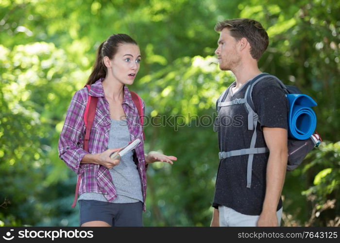 hiking couple with map discussing over direction in forest