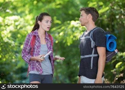 hiking couple with map discussing over direction in forest